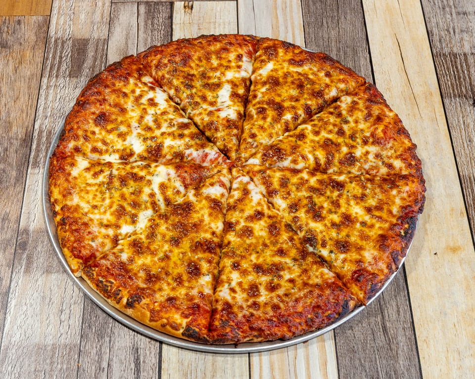 A whole cheese pizza, cut into eight slices, on a metal pan over a rustic wooden table.