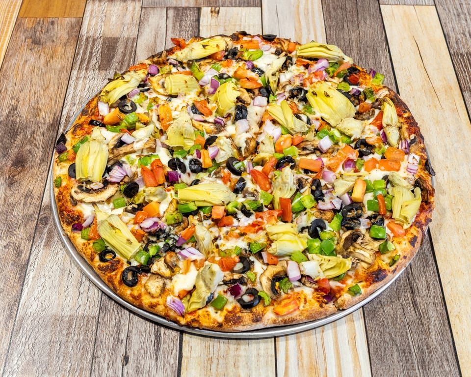 A whole vegetarian pizza with artichokes, mushrooms, olives, bell peppers, and onions.