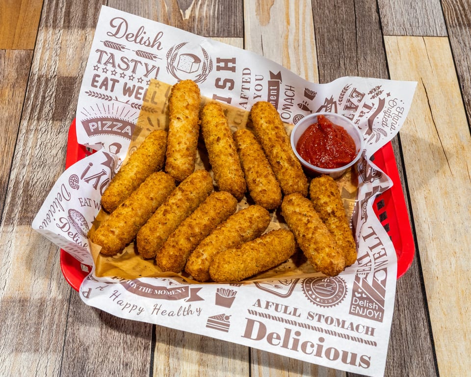 A red basket filled with golden-brown mozzarella sticks and a small cup of marinara sauce.