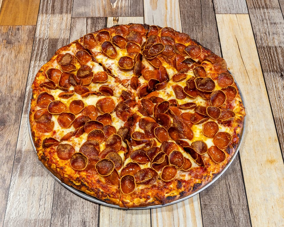 A whole pepperoni pizza with a crispy crust and melted cheese on a wooden table.