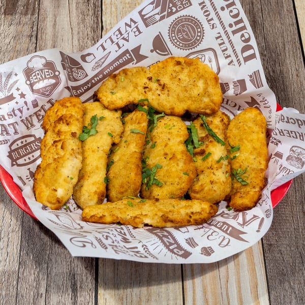 Golden-brown fried chicken tenders and nuggets, garnished with parsley, served in a red basket with patterned paper.
