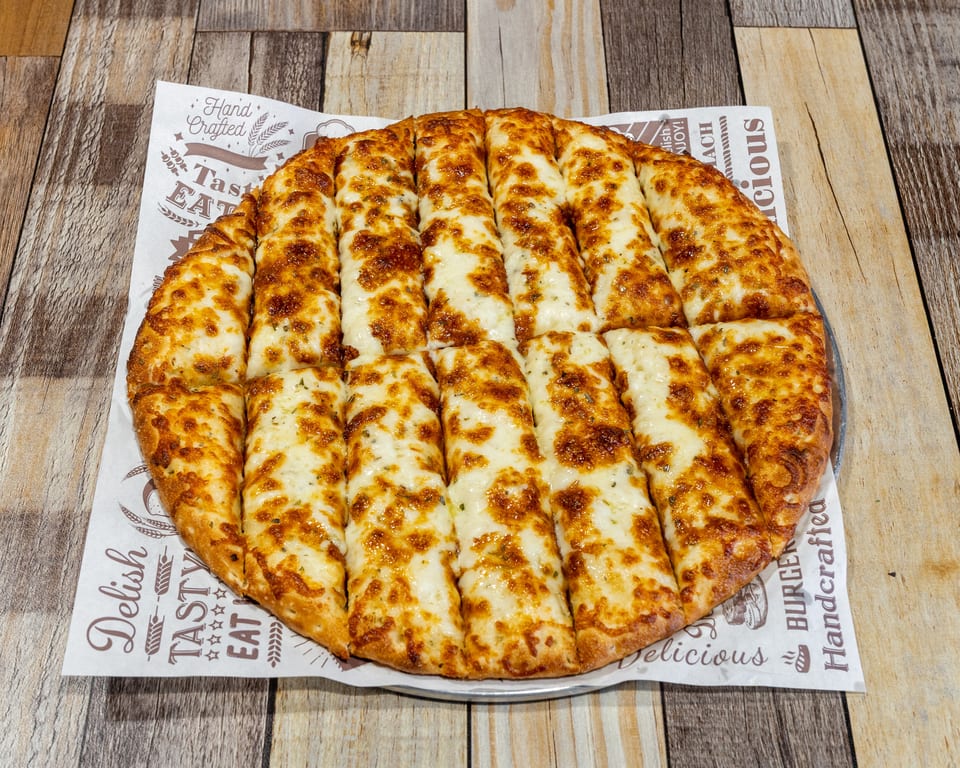Cheesy breadsticks, golden brown and cut into strips, on a branded paper liner.