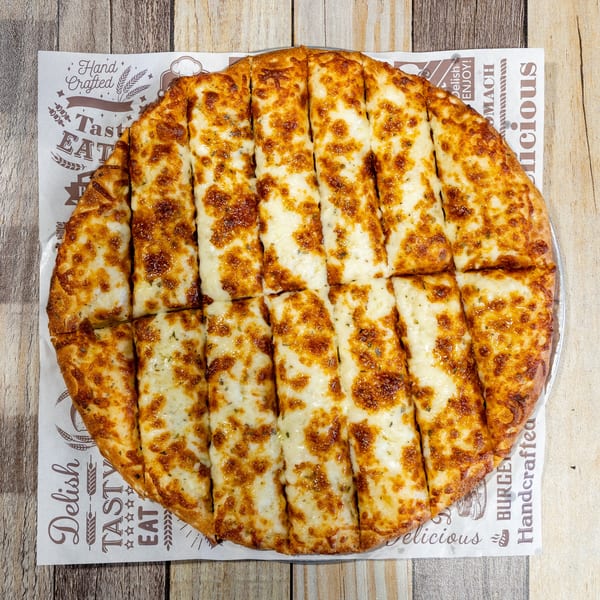 Golden brown cheesy breadsticks, cut into strips, served on branded parchment paper on a wooden table.