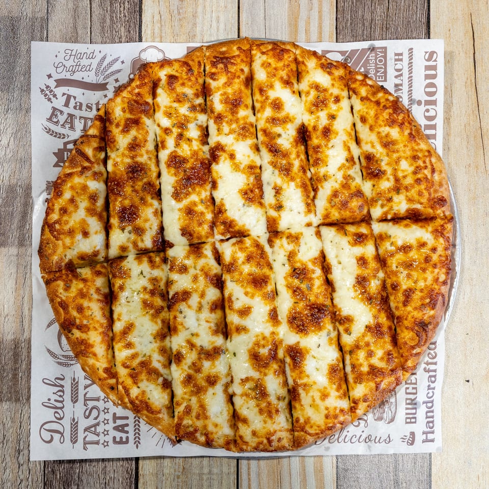 Golden brown cheesy breadsticks, cut into strips, served on branded parchment paper on a wooden table.